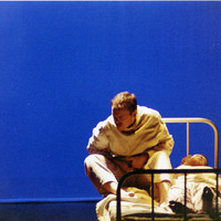 Colour photograph of two actors on a bed in The Man With Two Kisses by Pan Pan Theatre Company